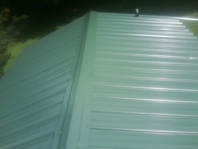 New green metal panels meeting at the ridge of a roof in Whiting
