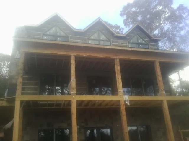 Dormers and porch framing on a large log home under construction — Roof Coating work by our crew in Whiting
