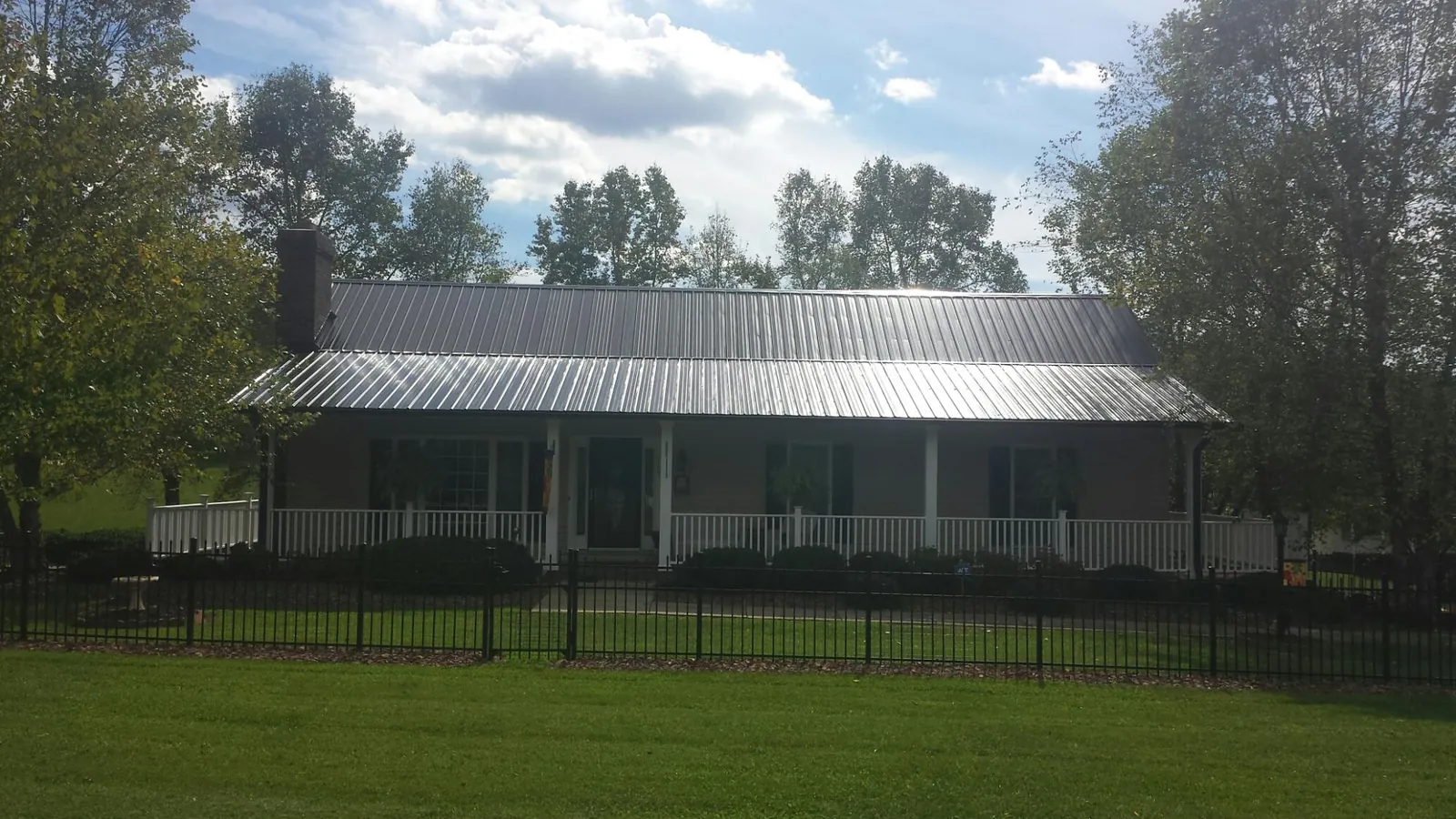 Gray metal roof on a brick ranch with a full width front porch — Gutter Guard Installation work by our crew in Whiting
